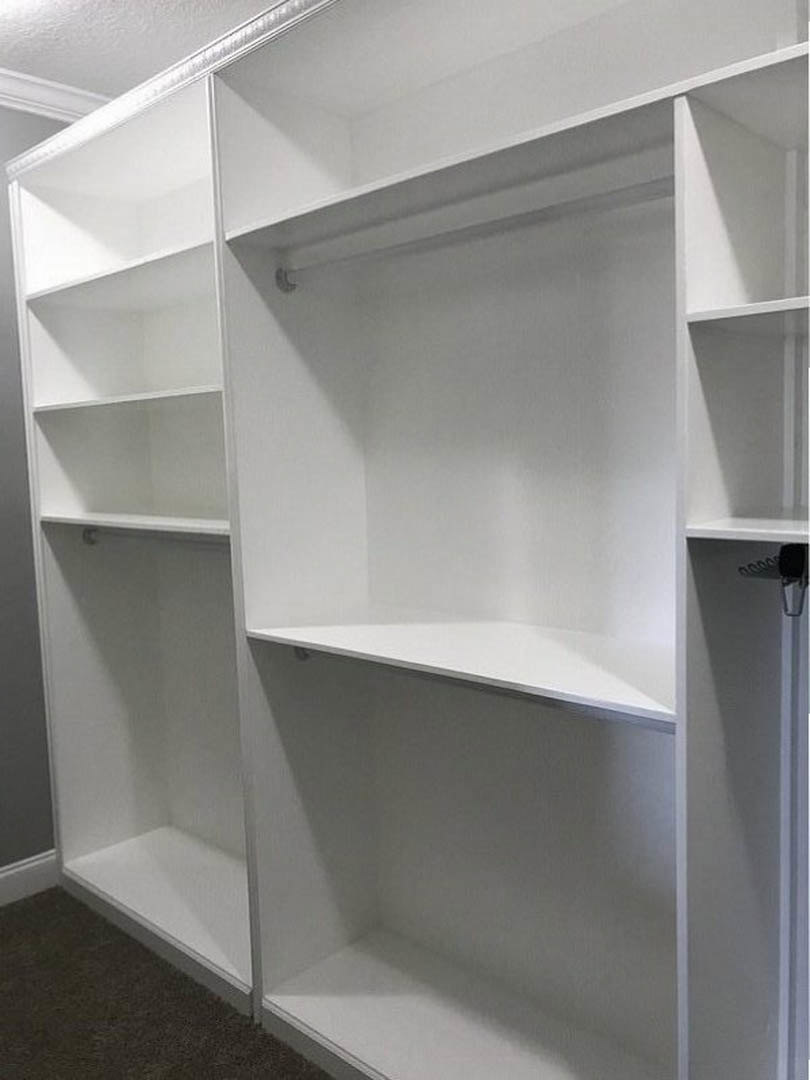 Built-in white shelving unit against a light-colored wall in a spacious room with hardwood flooring