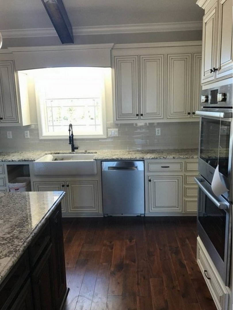 White shaker cabinets, speckled granite countertops, stainless steel appliances, undermount sink, light gray tile backsplash, hardwood flooring, recessed lighting