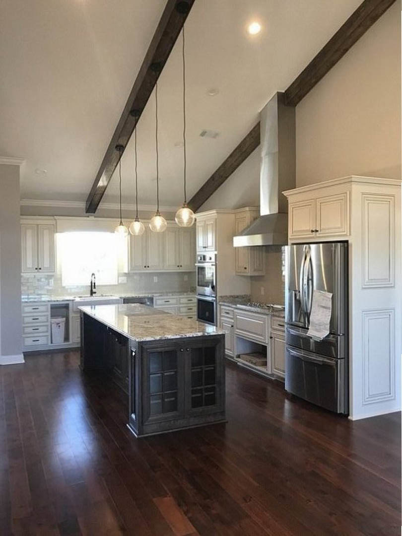 Kitchen with wood plank flooring and matching wood ceiling, black glass-front cabinet, stainless refrigerator with paper attached, white countertop, and modern cabinetry.