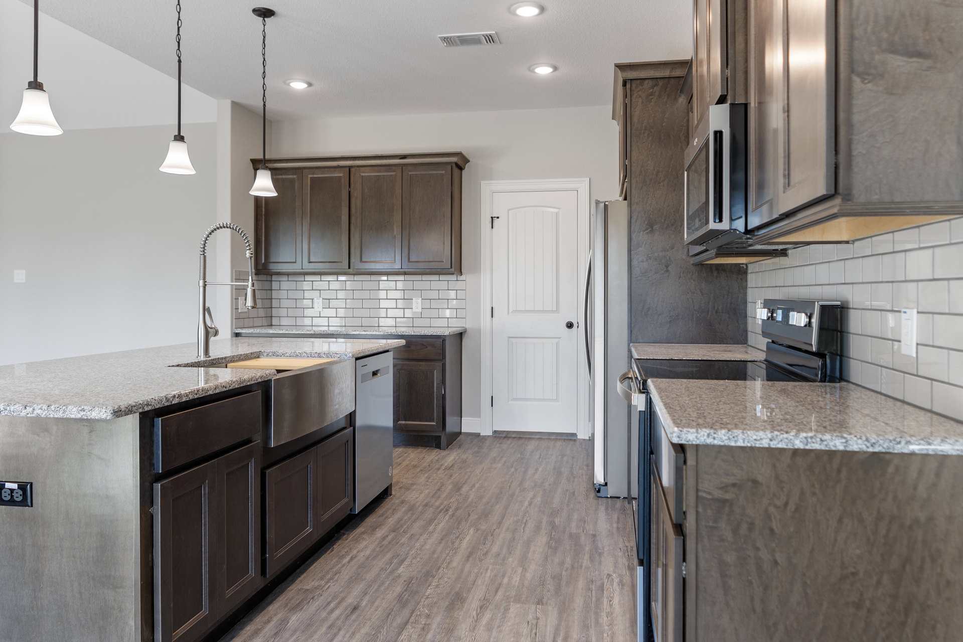 Kitchen with light wood flooring, white walls, white cabinetry, stainless steel stove, round metal door knob on a white door, metal pole with chain, close-up of modern light