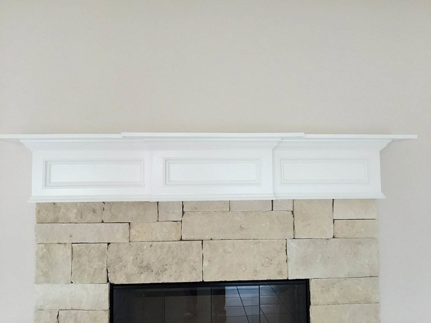Stone fireplace with white mantel and trim, white wall, built-in shelf, hearth