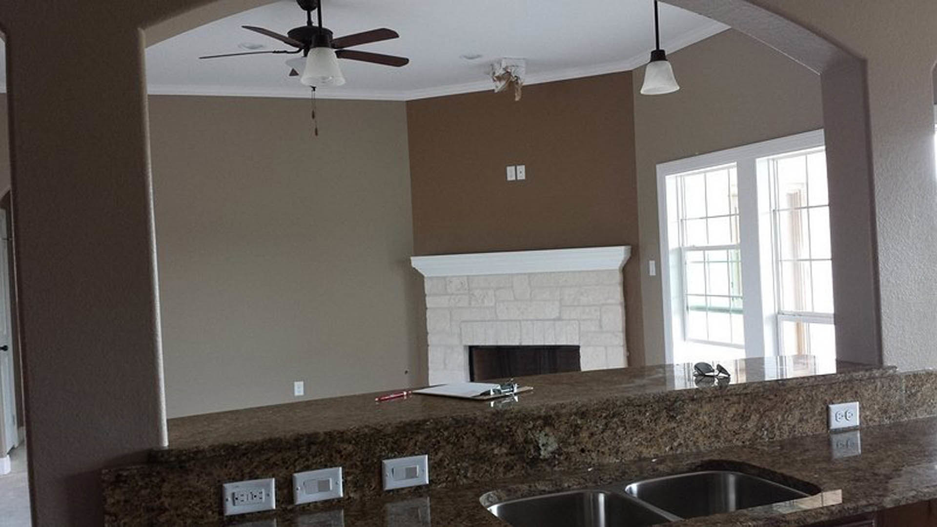 Modern kitchen featuring dual stainless steel sinks, white quartz countertops, light wood cabinetry, and a white electrical outlet on the backsplash.