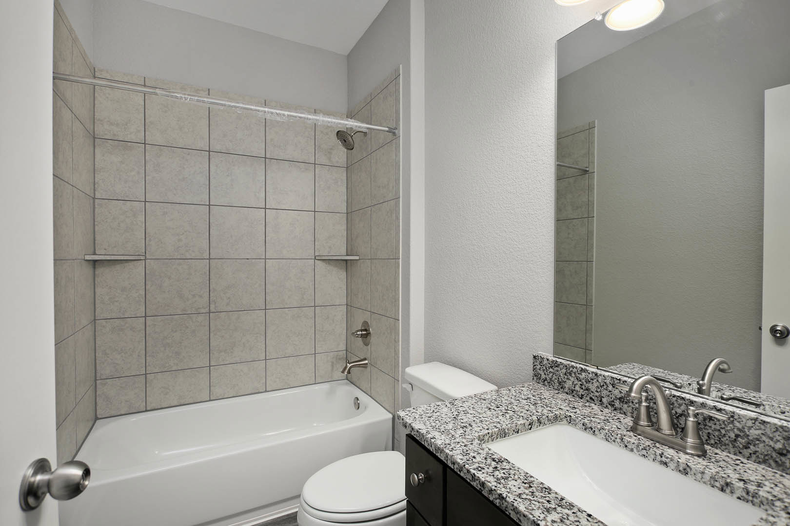 Modern bathroom with white porcelain sink, chrome faucet, wall-mounted toilet, freestanding bathtub, tiled walls, glass shower enclosure, and recessed ceiling light