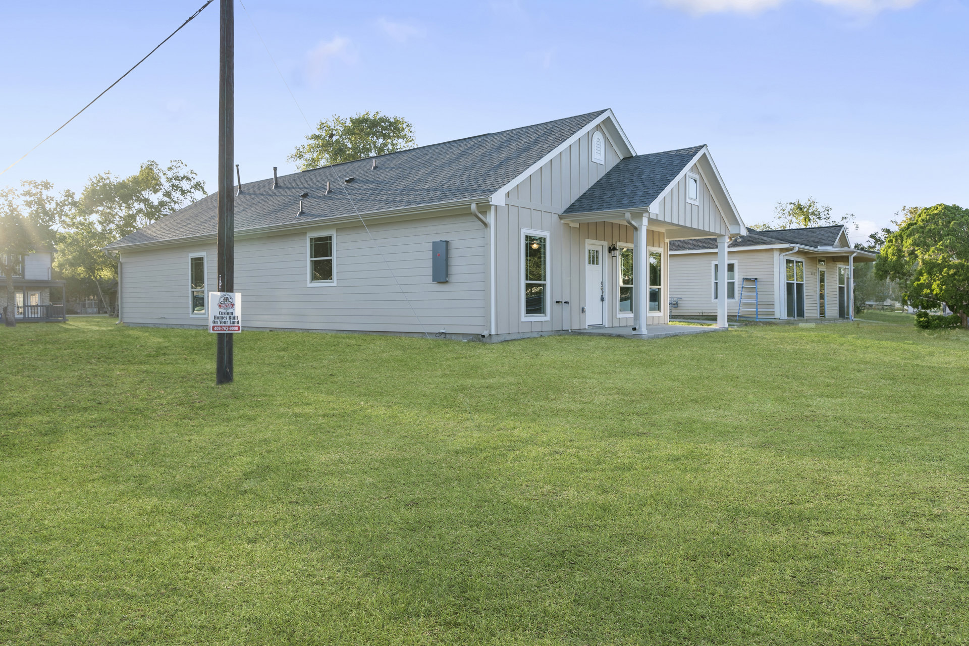 Two-story house with white siding, gabled roof, and multiple windows, set on a green lawn with a wooden telephone pole and leafy tree; Robert Frost Farm sign visible in the