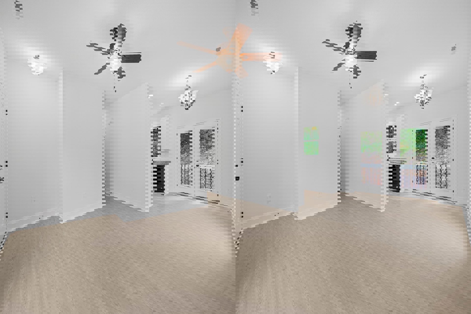 Ceiling fan with light fixture mounted on white plaster ceiling, hardwood floor, double glass-paneled doors, white walls, chandelier with white lamps