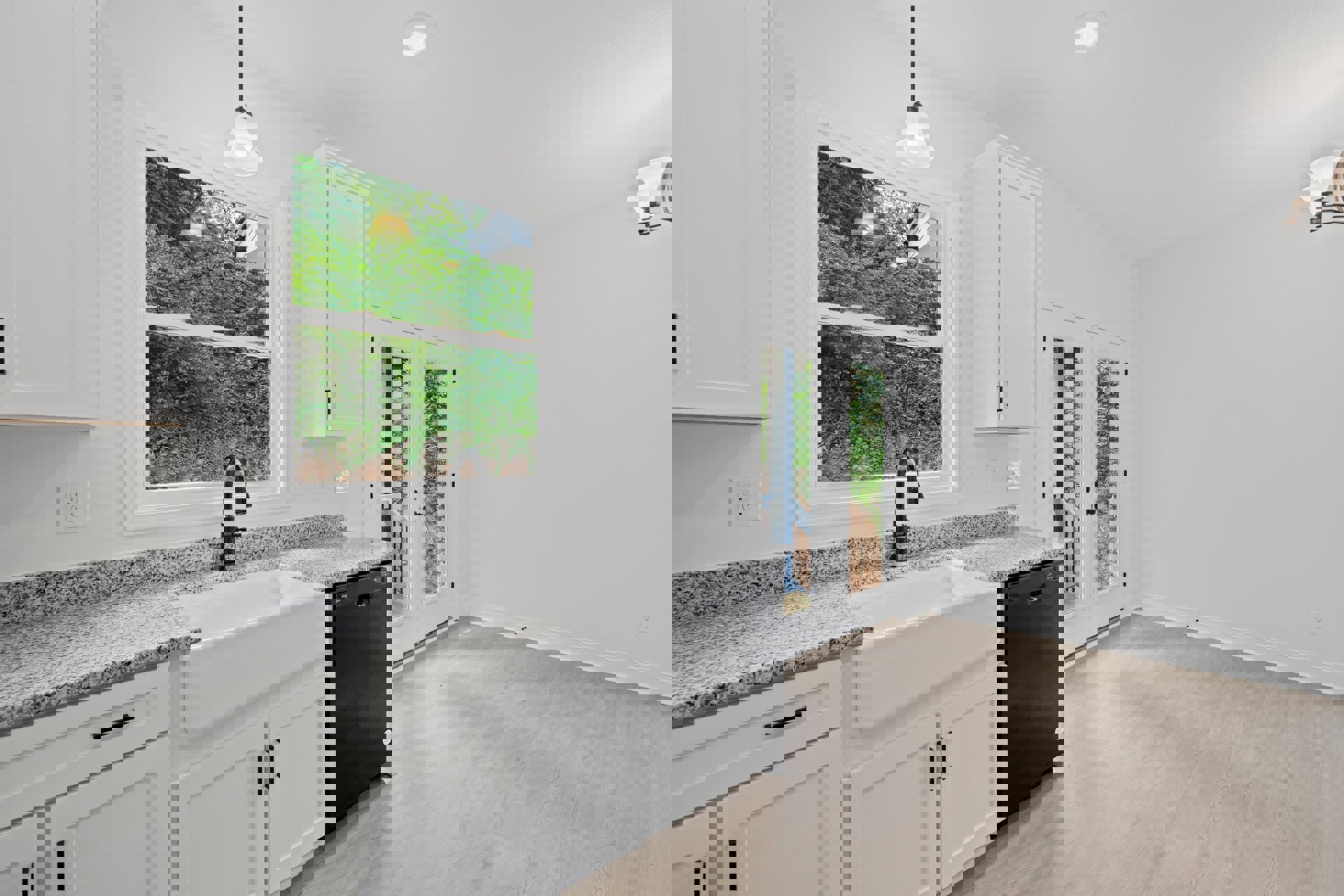 Modern kitchen with white cabinetry, stainless steel sink beneath a window overlooking trees and a neighboring house, light-colored countertops, built-in appliances, and recessed