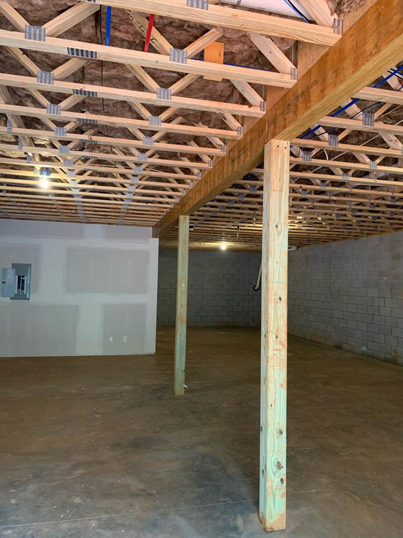 Exposed wooden ceiling beams, concrete floor, white wall with mounted boxes, close-up of wood post, modern indoor finishes
