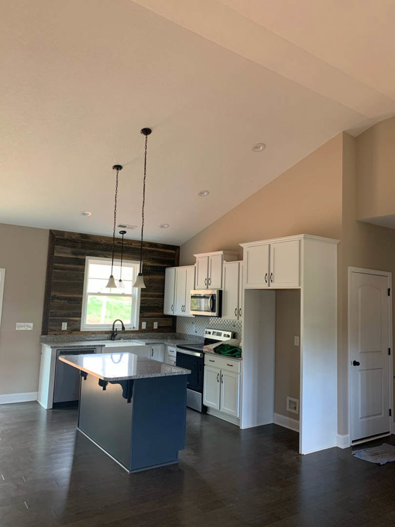 Kitchen featuring a marble-topped island, built-in microwave, dark wood flooring with blue base, white cabinetry, black door knob, window with pendant light fixture
