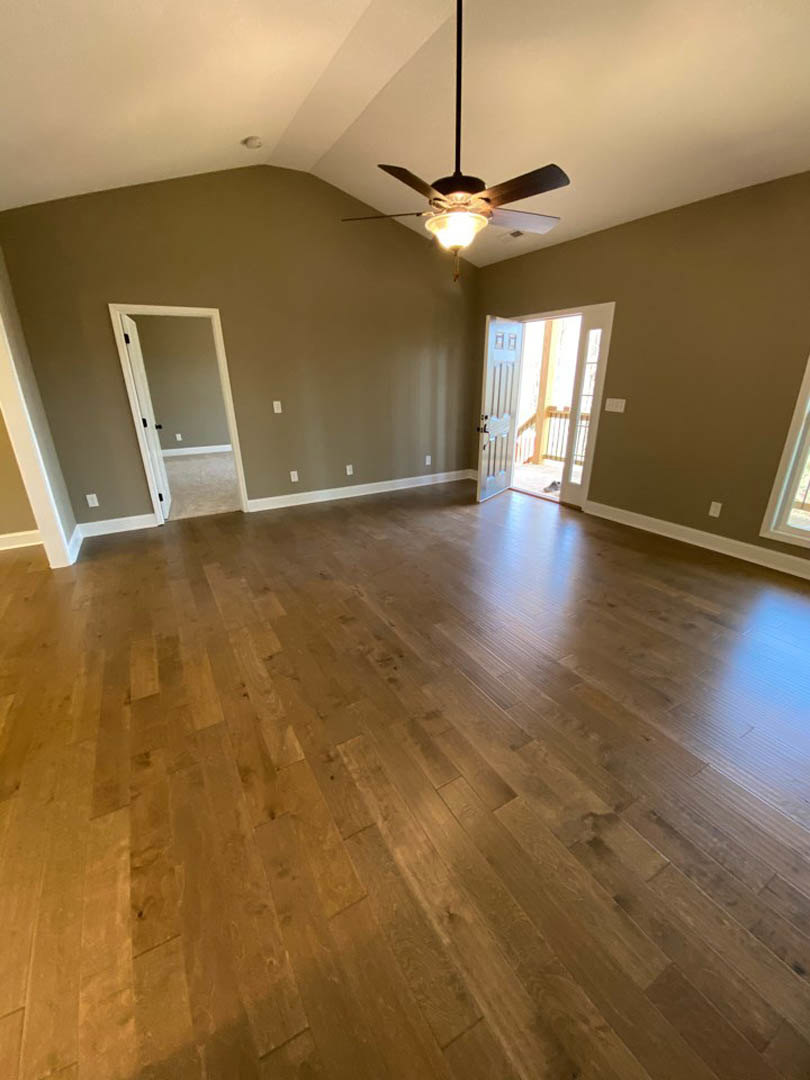 Ceiling fan with light fixture, hardwood flooring, glass door, wall mirror, neutral painted walls