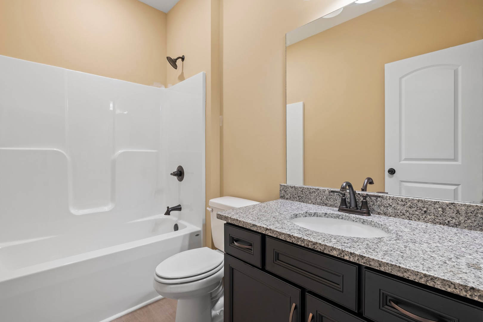 Modern bathroom featuring a white bathtub, toilet, and sink with chrome fixtures, light tile walls, and a curved-top white door