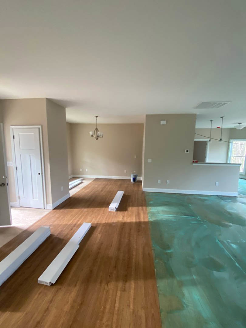 Wood flooring and white baseboards in a room with a white door featuring a black handle, a white rectangular object on a wooden surface, a close-up of a glass surface, a white