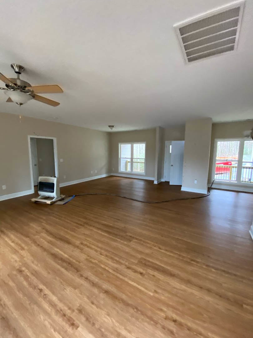 Hardwood floor room with ceiling fan and light fixture, white-framed window, white computer on floor, vent on ceiling