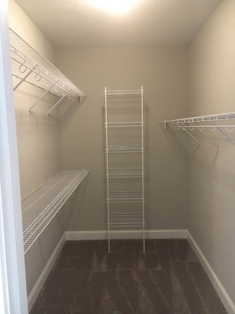 White built-in shelves mounted on a plaster wall above light carpet flooring in a modern room.