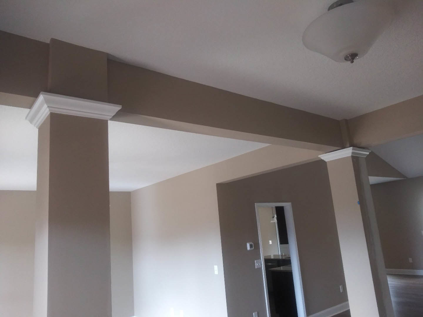 White ceiling molding and recessed light fixture above a neutral-toned room with a paneled door and smooth plaster walls.