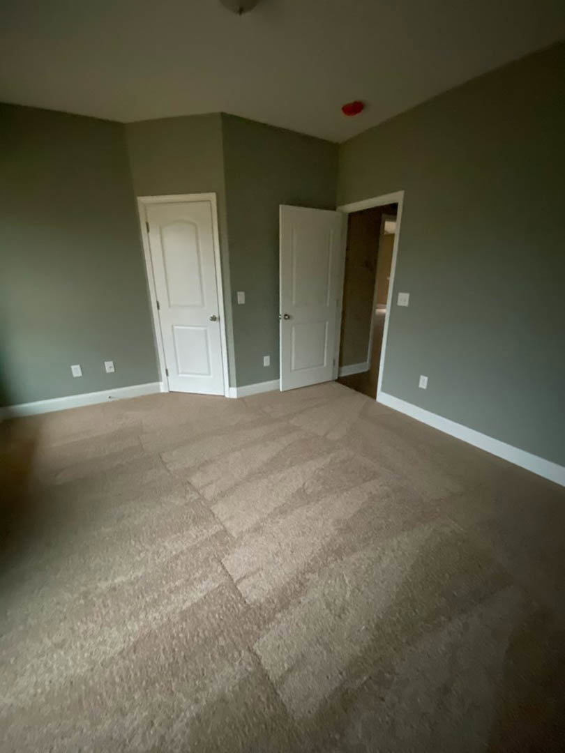 Carpeted room with two white doors featuring silver handles, white walls, and ceiling