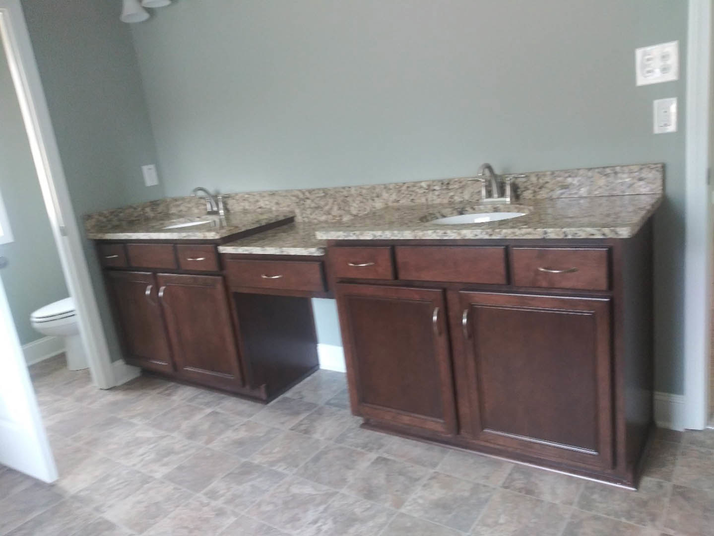 Bathroom with marble countertops, tile flooring, wooden vanity cabinet, chrome faucet, and white toilet