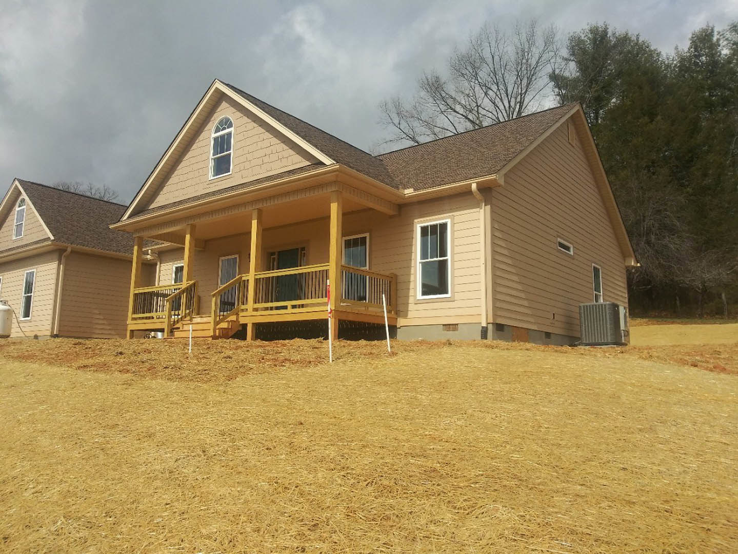 Spacious front porch with white-framed windows, gabled roof, and mature trees in the background