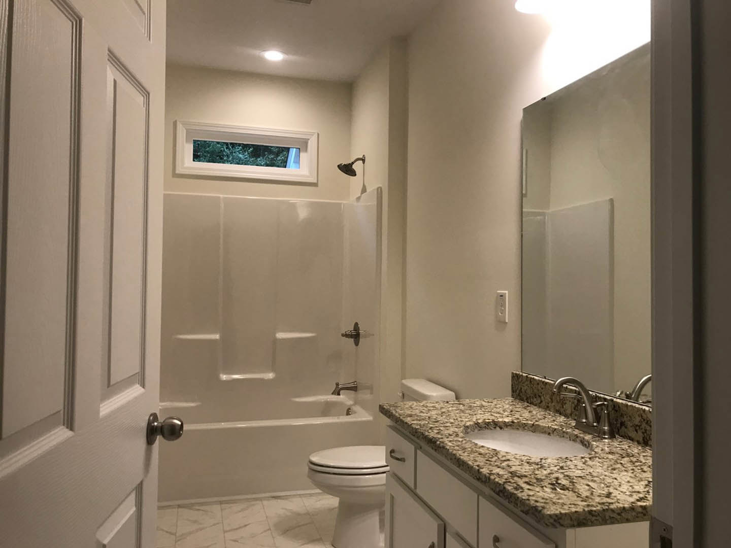 Modern bathroom featuring white tile walls, a rectangular sink with chrome faucet, a close-up of a toilet, a glass window with blue tint, a white shower with built-in steps, and a