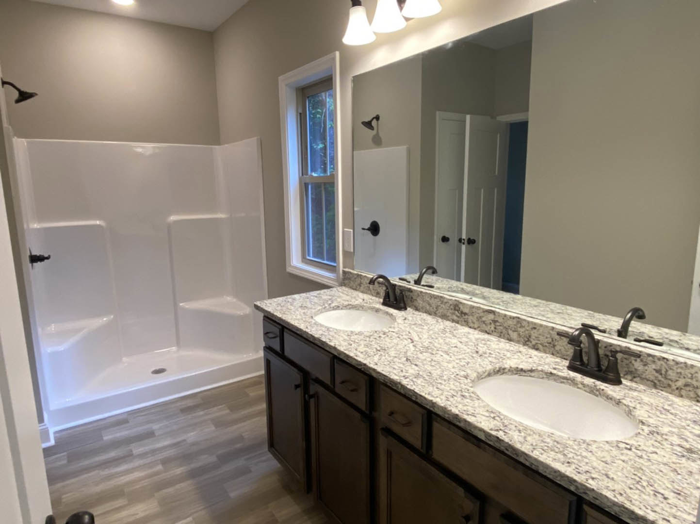 Bathroom with a wide framed mirror above a rectangular sink, white tile walls, chrome faucet, and built-in cabinetry.