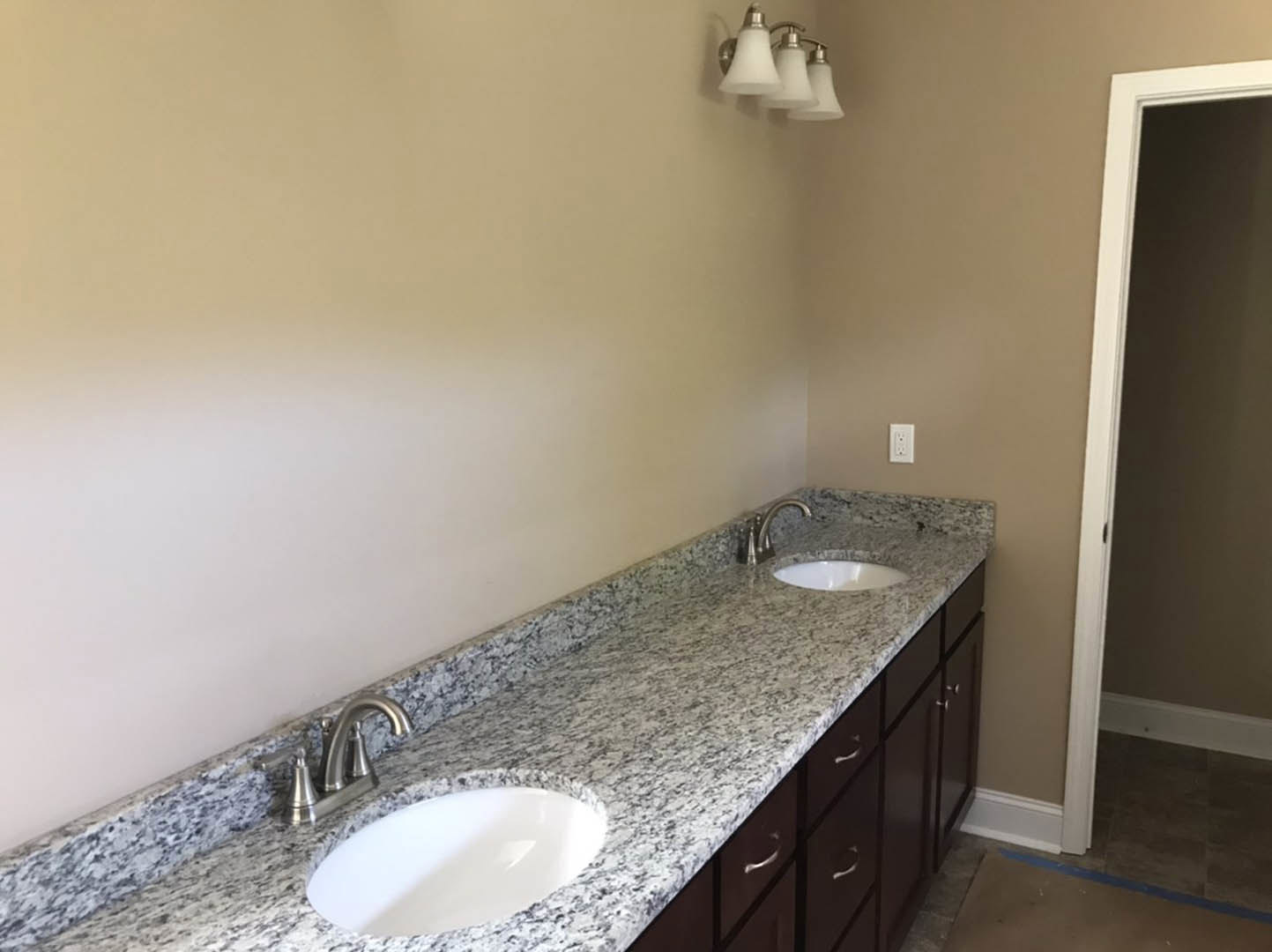 Double vanity bathroom with undermount sinks, brushed nickel faucets, quartz countertop, white tile backsplash, and a modern light fixture with white shade above large mirror.