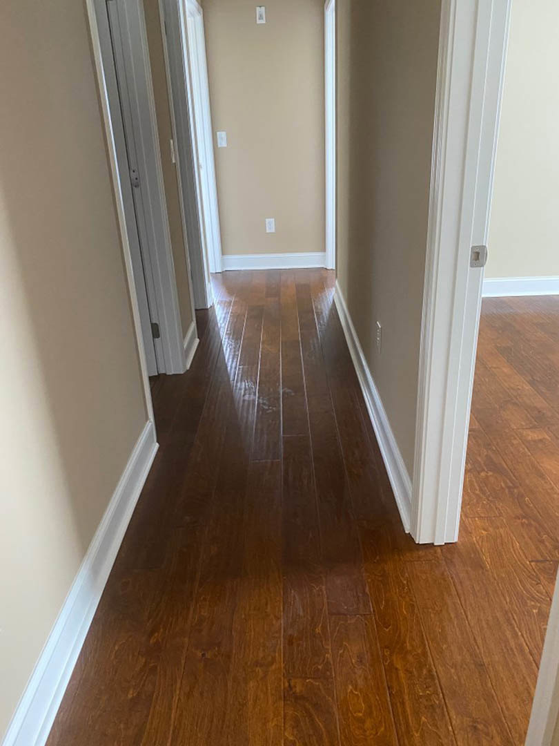 Hallway with light hardwood floor, white walls, white door frame, and baseboard trim