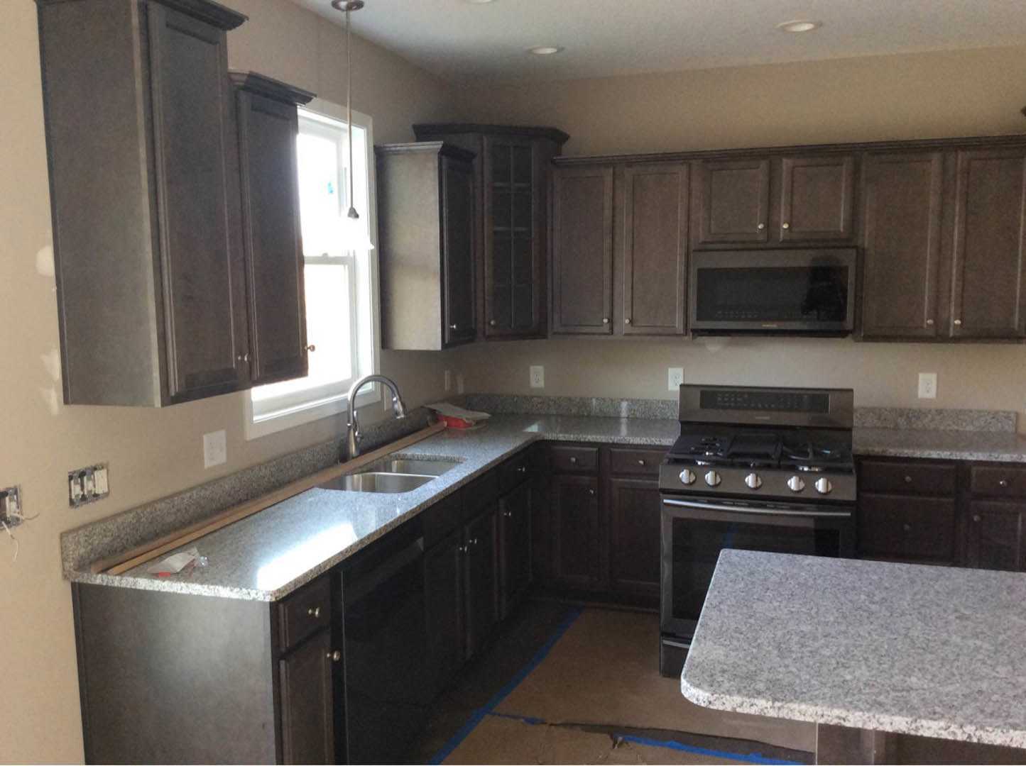 Granite countertops, stainless steel stove, white cabinetry, undermount sink, and tile backsplash in a modern kitchen