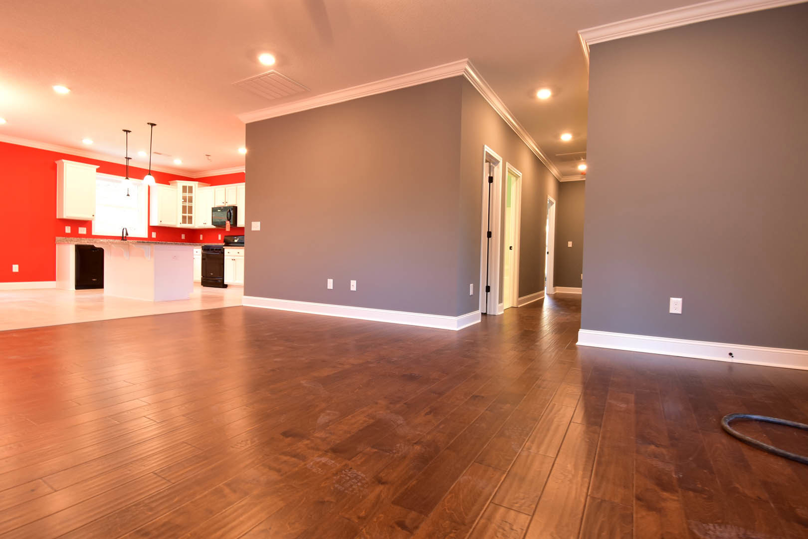 Open-concept kitchen with white cabinetry, black island, hardwood floors, recessed lighting, and plaster walls