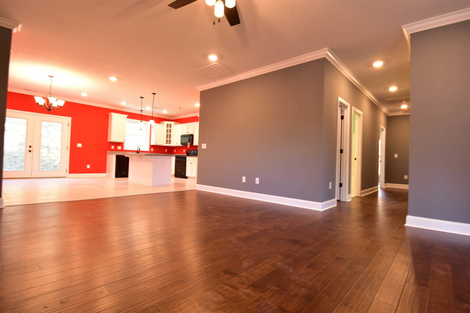 Hardwood floor room with ceiling fan, double frosted glass doors, neutral walls, and modern lighting fixtures