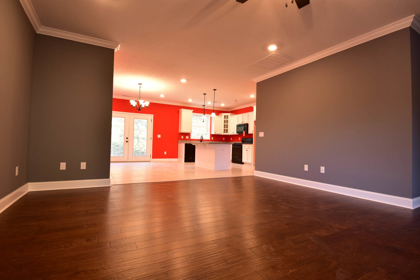 Open kitchen and dining area with wood flooring, white walls, glass-paneled double doors, modern lighting fixtures, and sleek cabinetry