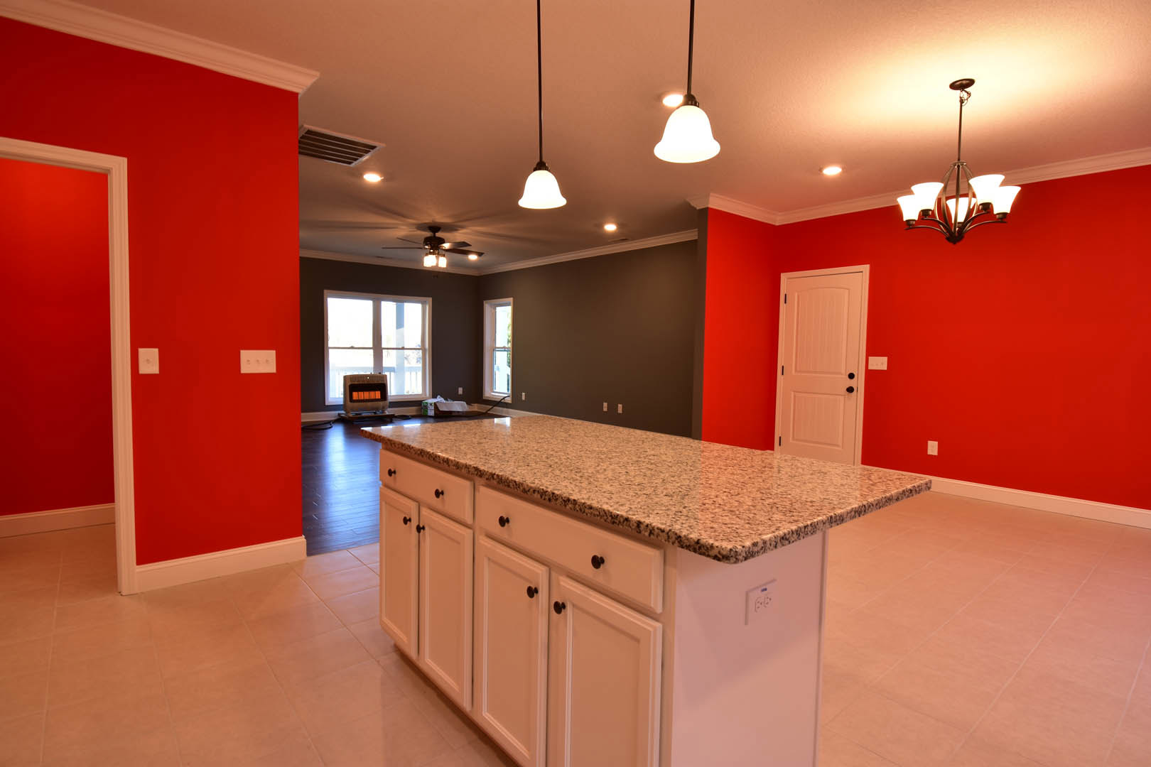 Quartz kitchen island with undermount sink, white cabinetry, stainless steel faucet, pendant lighting, hardwood floors, and built-in appliances
