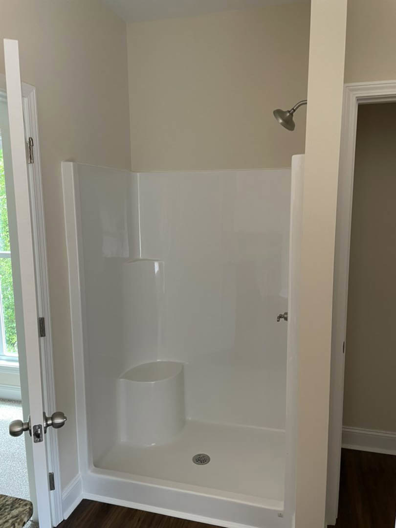Glass-enclosed shower with chrome showerhead, white tile walls, and built-in niche in modern bathroom