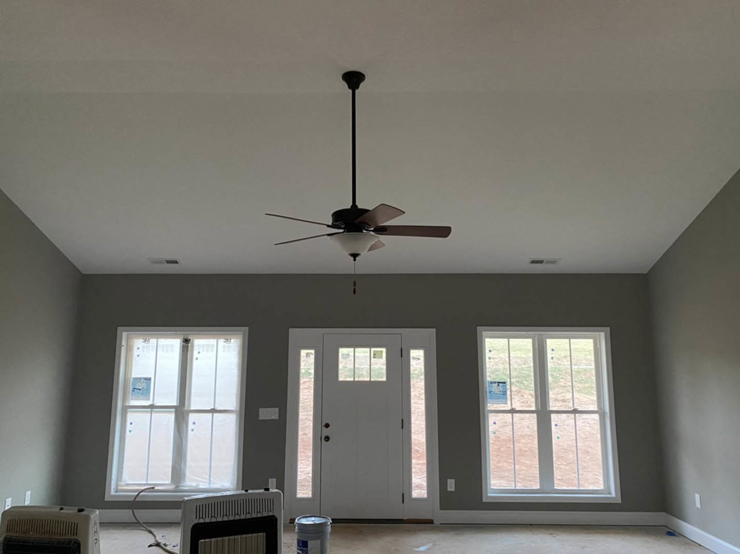 Ceiling fan with light fixture mounted on white ceiling, window with sign, white door with glass panes, close-up of air vent on wall