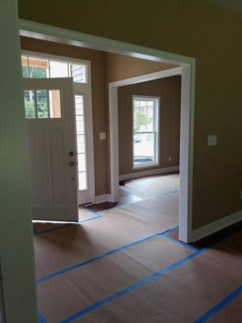 White interior room with wood flooring, white framed window, and white door featuring a glass panel and blue tape along the bottom edge