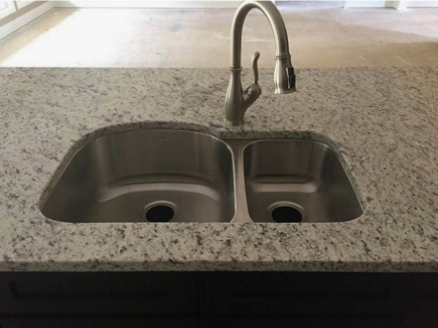 White porcelain bathroom sink with chrome faucet, set against a light wall, featuring a round drain and modern plumbing fixtures.