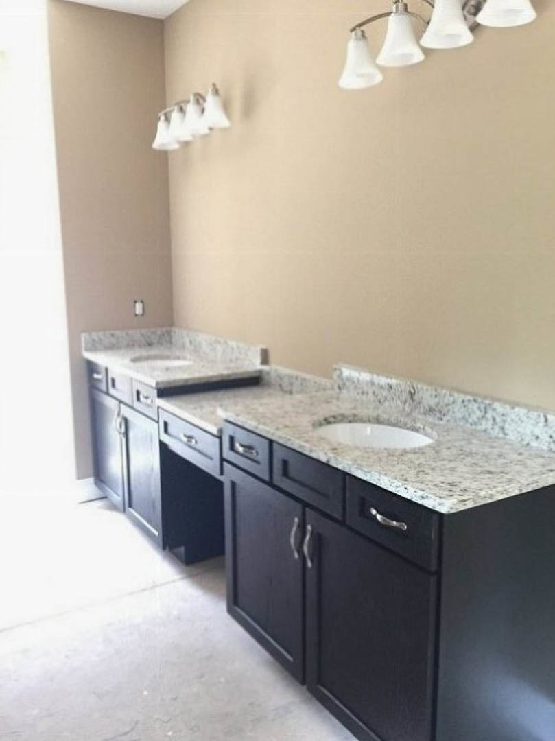 Double vanity with undermount sinks, quartz countertop, brushed nickel faucets, white shaker cabinetry, and a row of modern globe light fixtures above a large mirror.