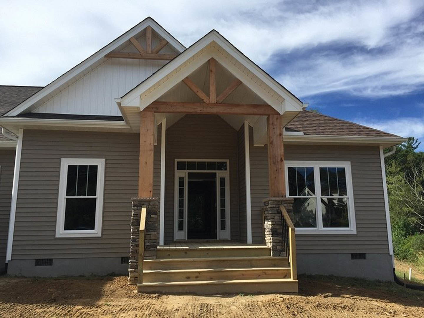 Two-story home with white siding, covered front porch, wooden stairs, white-framed windows, and glass-paneled front door