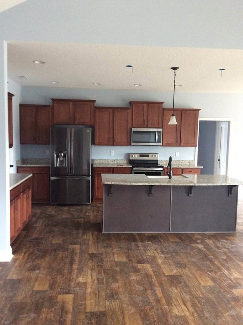 Kitchen with stainless steel refrigerator, stainless steel oven, marble countertop, white cabinetry, and granite flooring