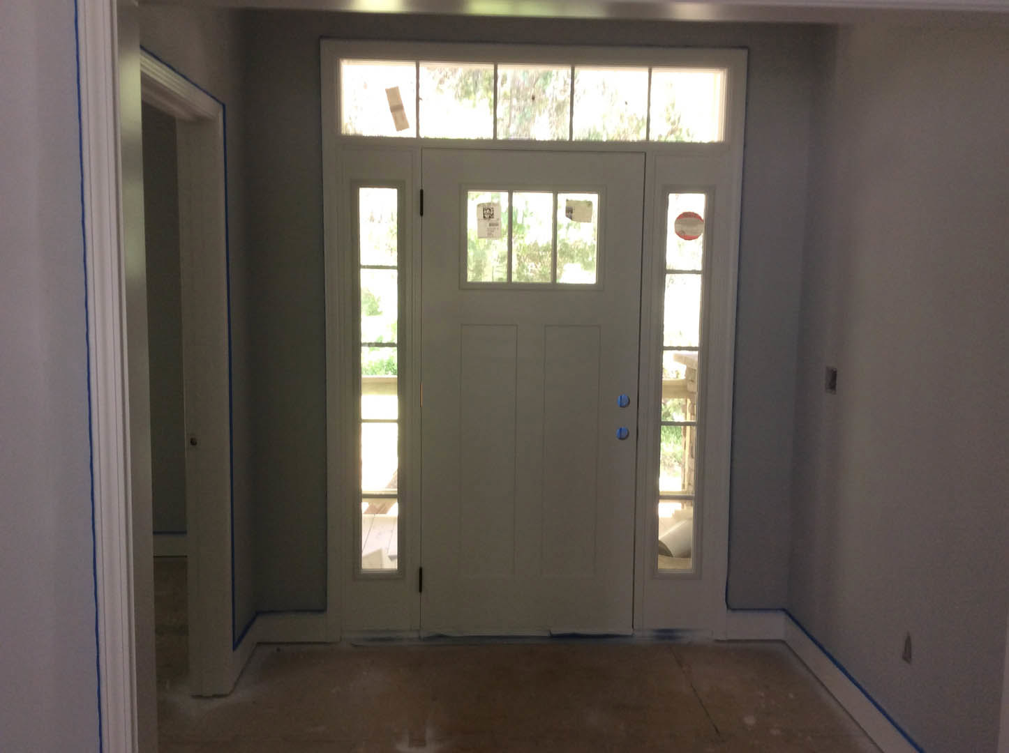 White door with glass panes and silver handle set in a light-colored room with hardwood flooring and a window displaying papers.