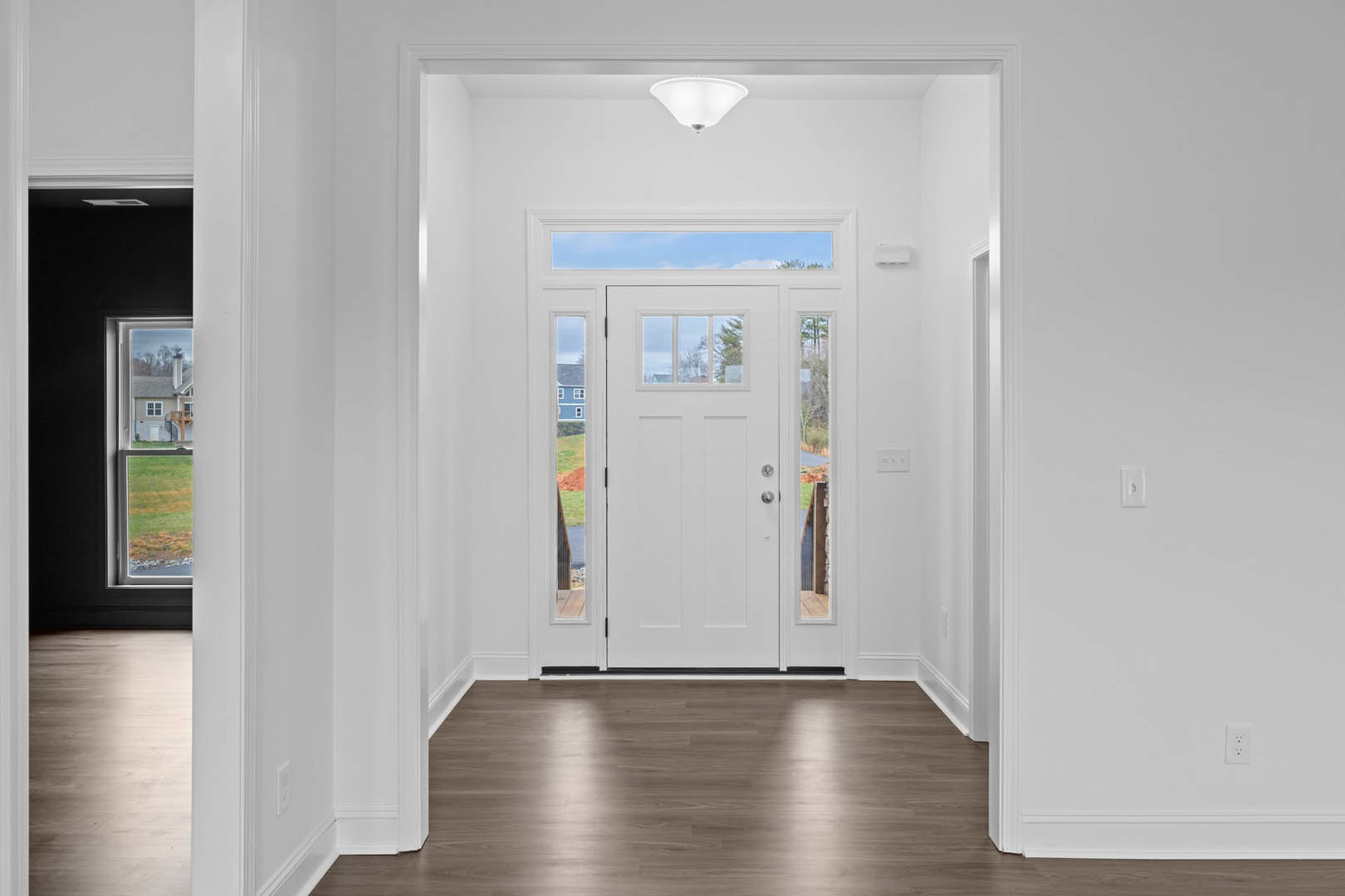 White door with glass panes set in a hallway with wood laminate flooring, white plaster walls, and ceiling.