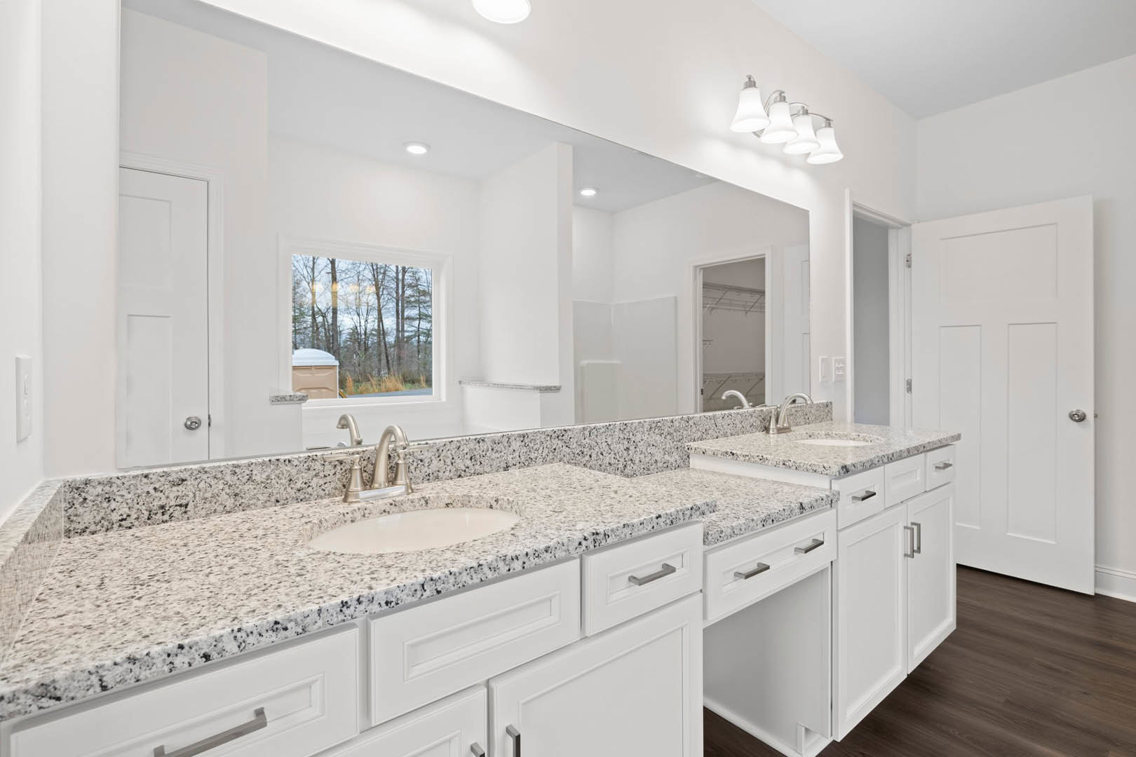Bathroom with white cabinets, granite countertops, undermount sink, chrome faucet, tile flooring, window overlooking trees, and modern light fixture