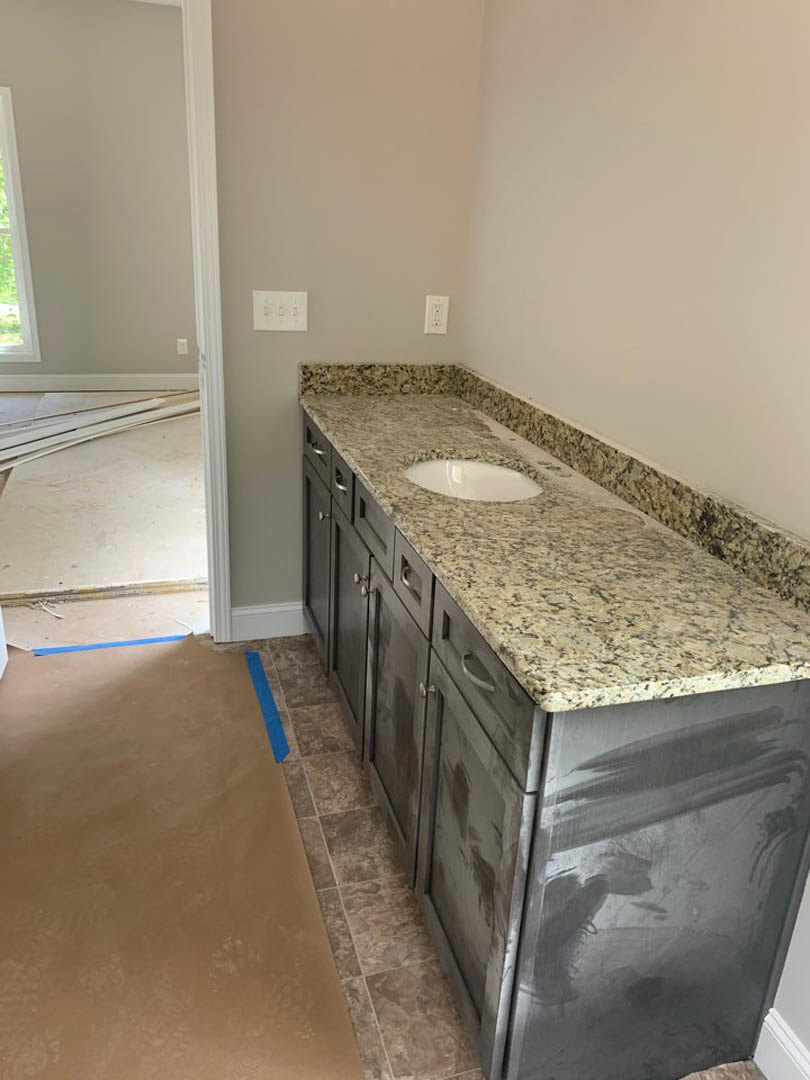 Bathroom with marble countertop, undermount sink, white cabinetry, chrome faucet, and tiled backsplash