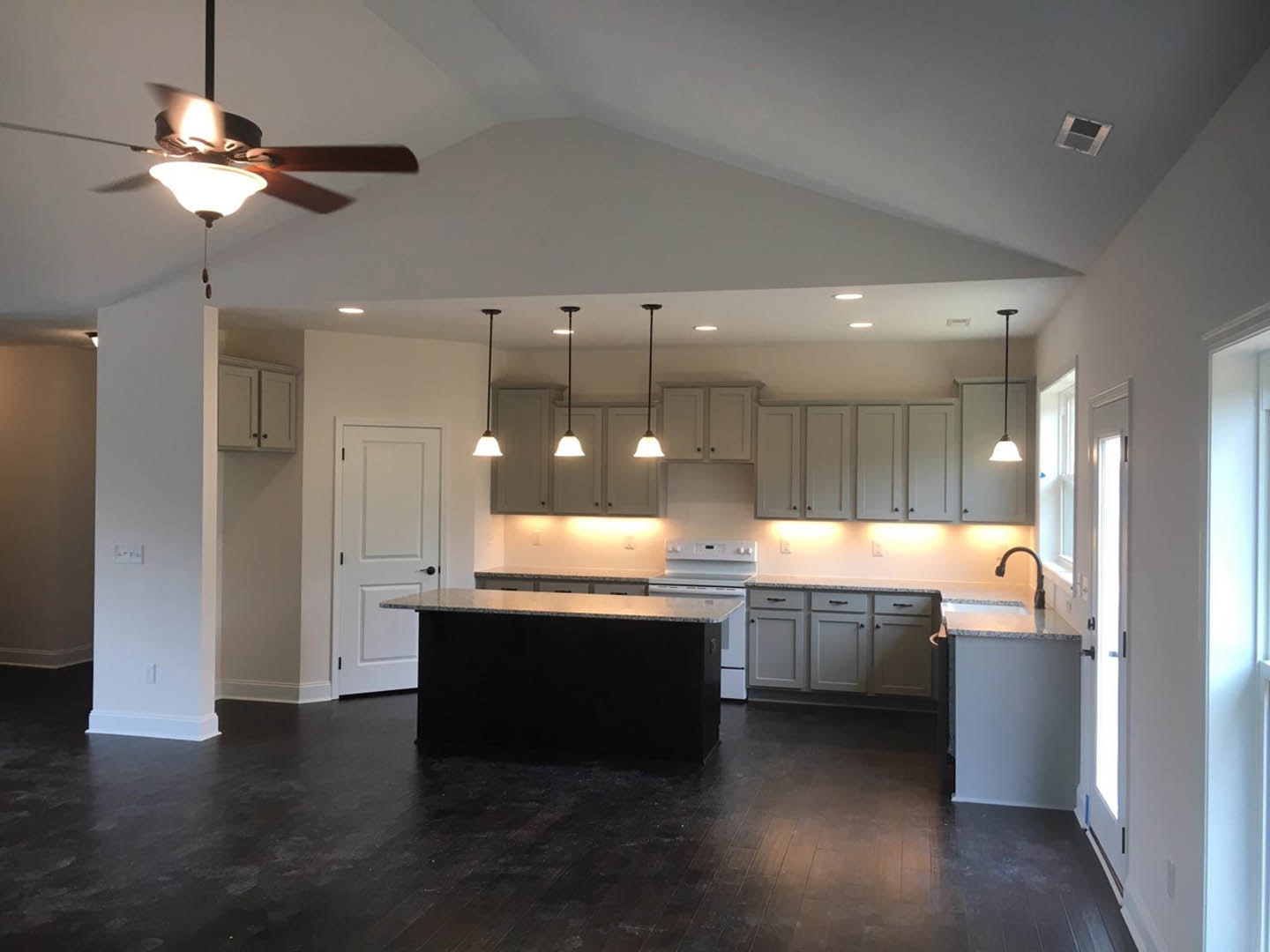 Kitchen featuring a matte black island with waterfall countertop, white cabinetry, stainless steel stove and oven, ceiling fan with light, light wood flooring, and white walls