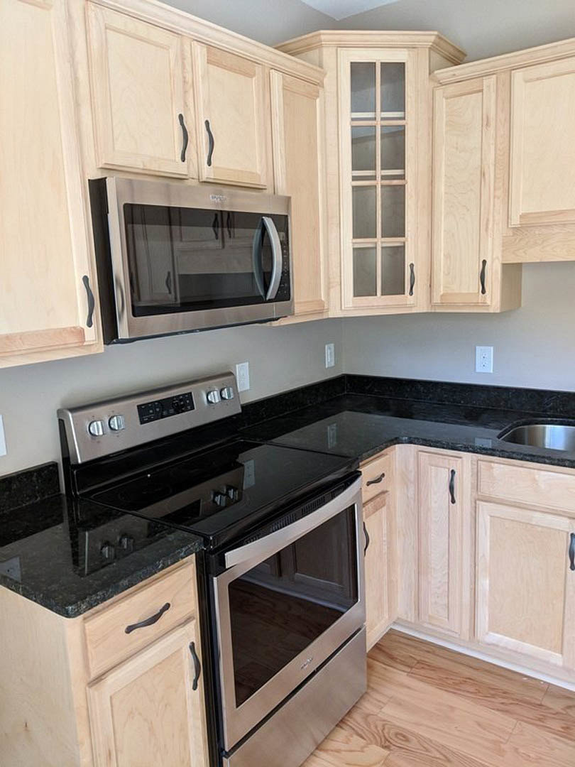 Kitchen featuring black countertops, wooden cabinets, stainless steel stove and oven, built-in microwave, and a window above the counter