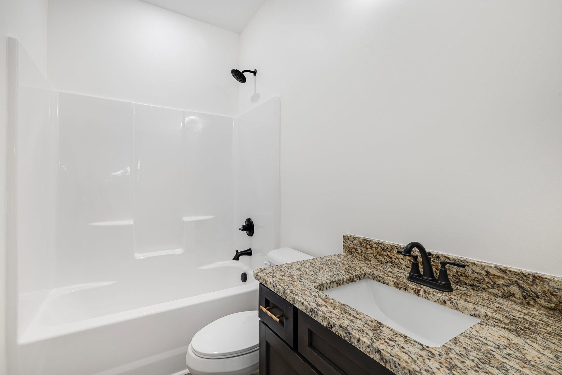 Modern bathroom with white tile walls, black fixtures including a curved shower head and faucet, white sink, and toilet