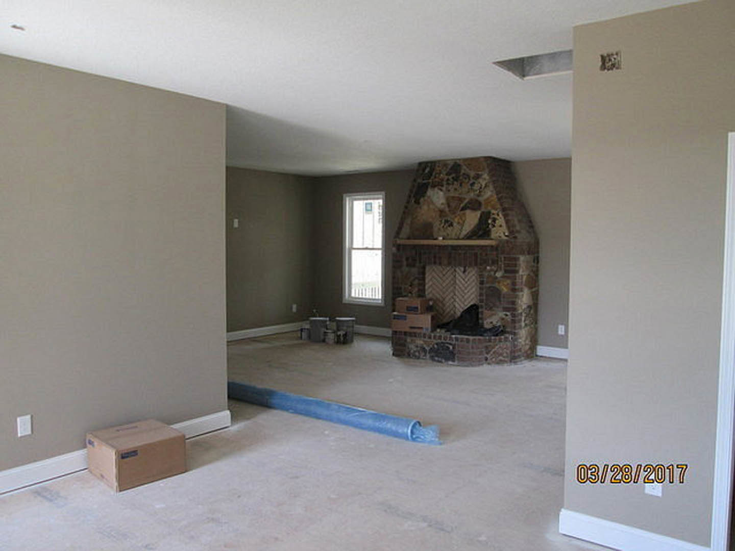 Living room with white walls, tile fireplace surround, wood flooring, large window with white trim, and a modern light switch on the wall