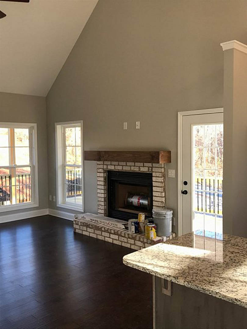 Living room featuring marble fireplace, hardwood floors, neutral walls, and large windows with metal railing