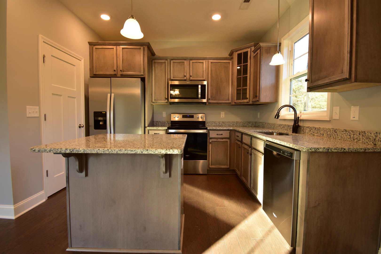 Granite countertops, stainless steel appliances, white cabinetry, kitchen island with marble top, built-in microwave, double-door refrigerator, undermount sink