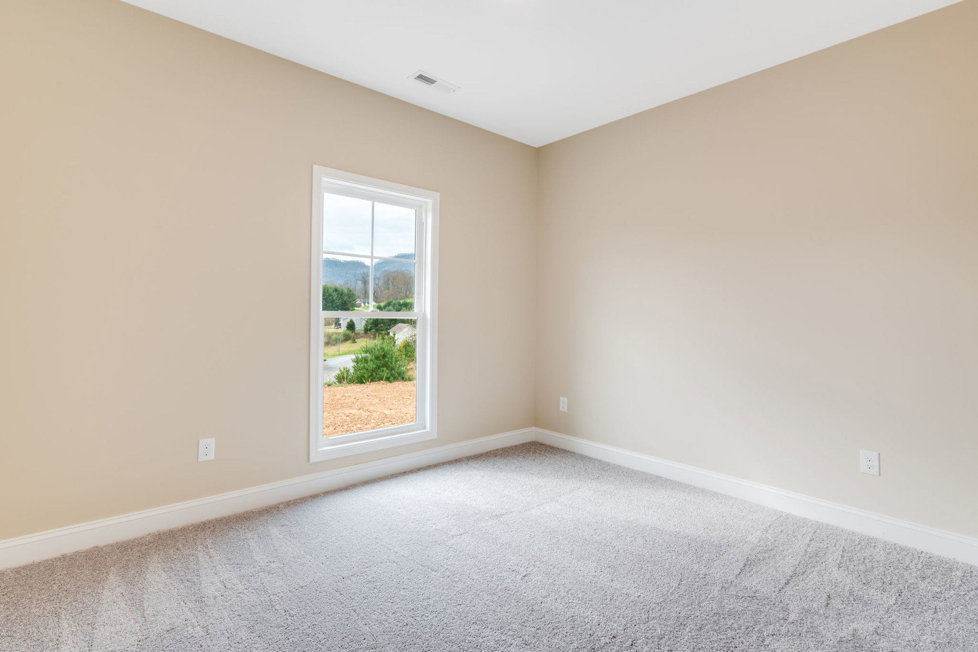 Bright room with white carpet, large window framing mountain and tree views, white walls, ceiling vent, and simple molding.