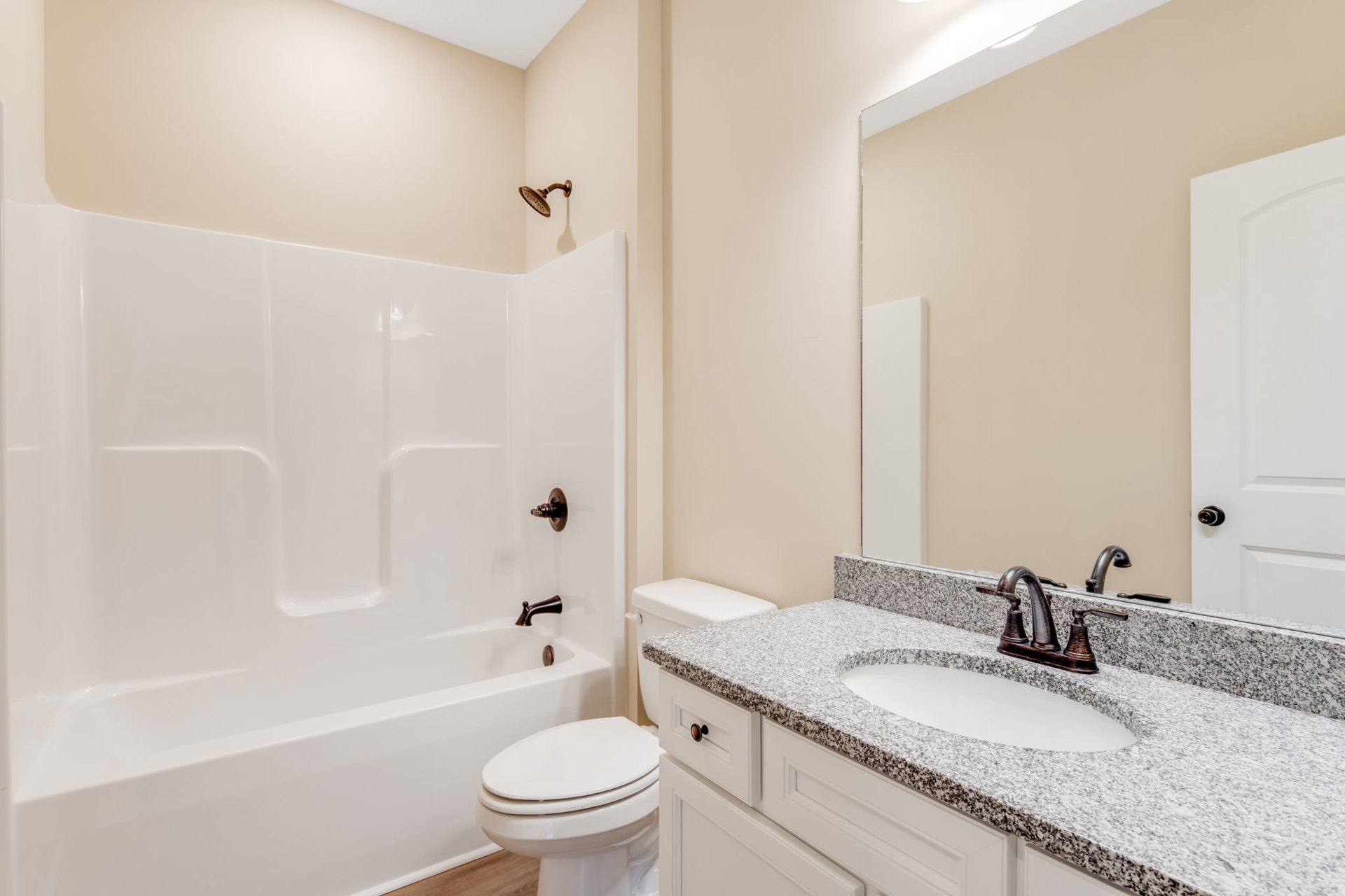 Modern bathroom with white porcelain sink, chrome faucet, glass-enclosed shower, tiled walls, white bathtub, and toilet; metal towel hook visible on wall