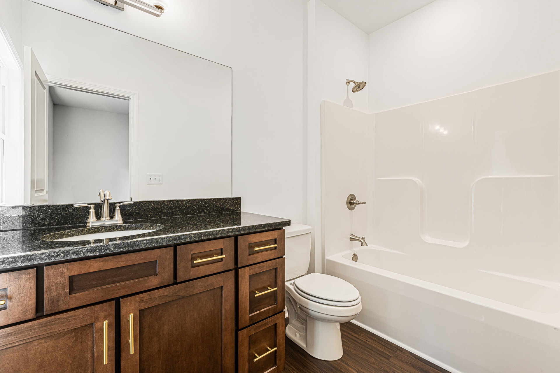 Modern bathroom featuring white tile walls, a white toilet with lid closed, rectangular sink with chrome faucet, light wood cabinetry, and stone countertop.